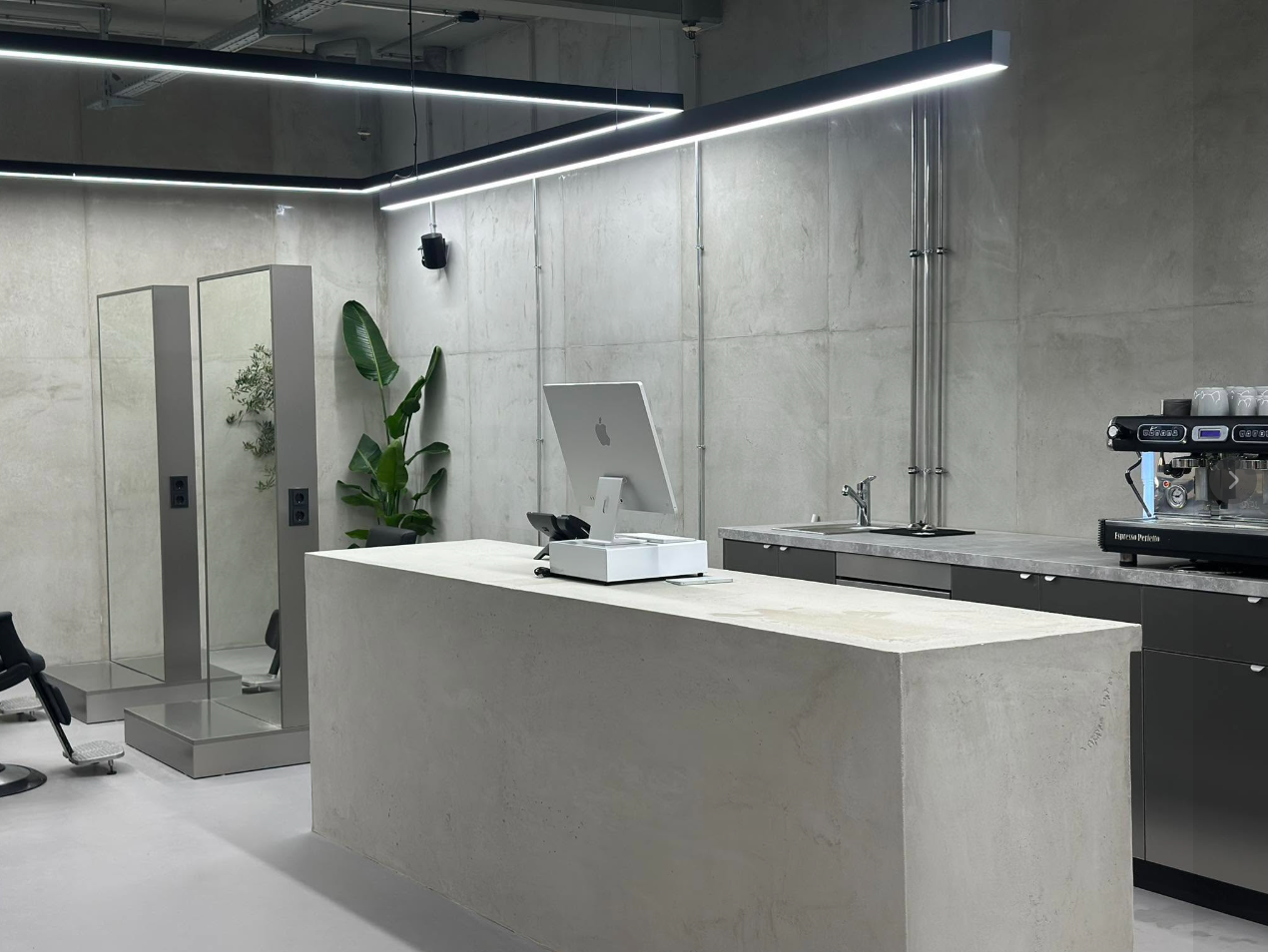 JOSAL Salon mit Betonwänden, großen Spiegeln und linearen LED-Leuchten